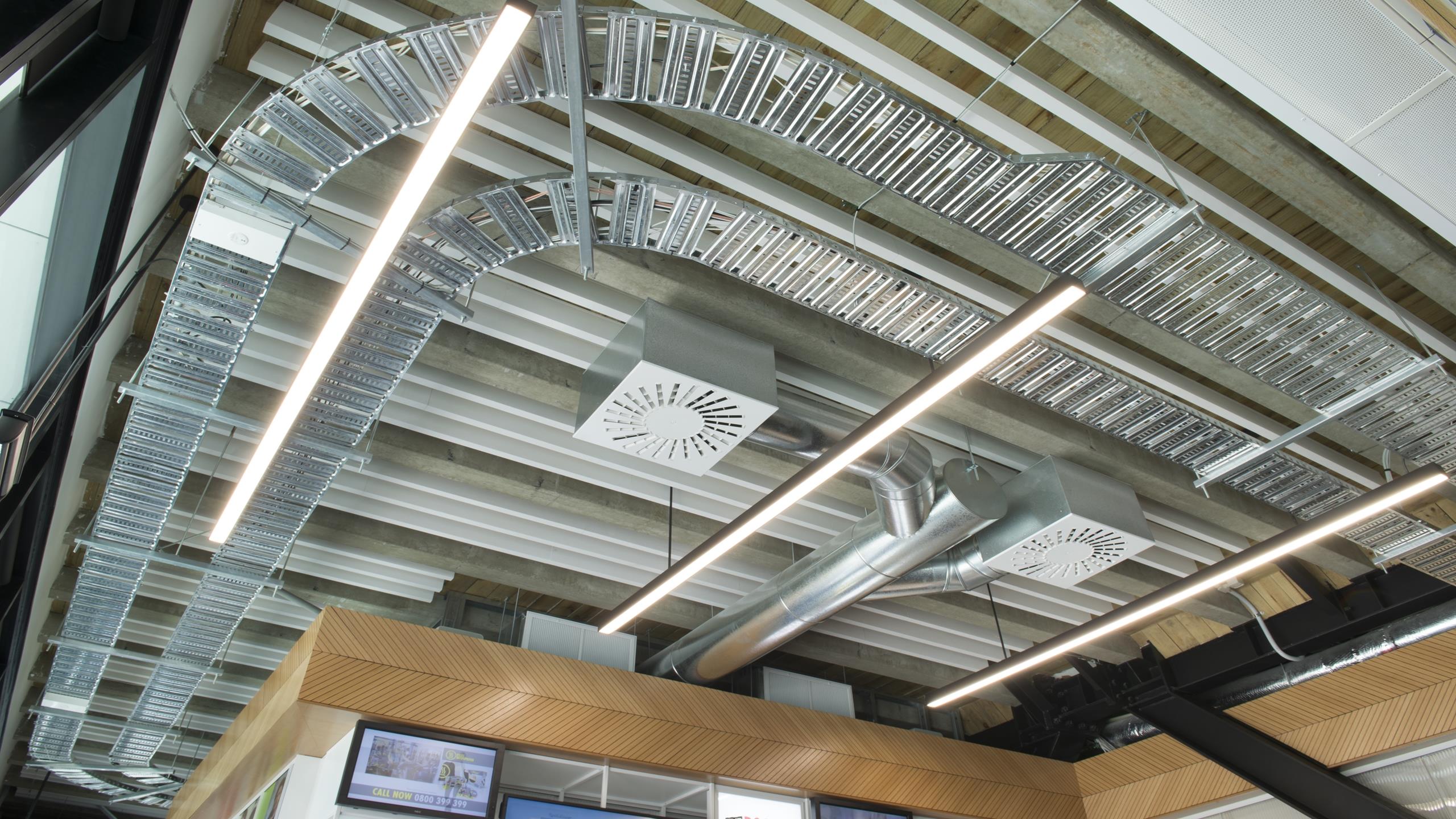 Media Works reception area showing white linear Baffle beams installed in exposed conduit ceiling plan